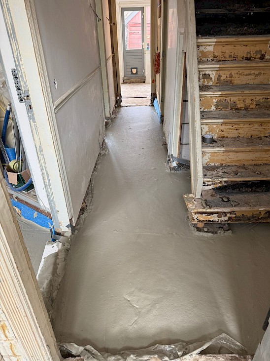 Naadloos schuimbeton in een gangpad als oplossing voor effectief de vloer isoleren rondom de trap.